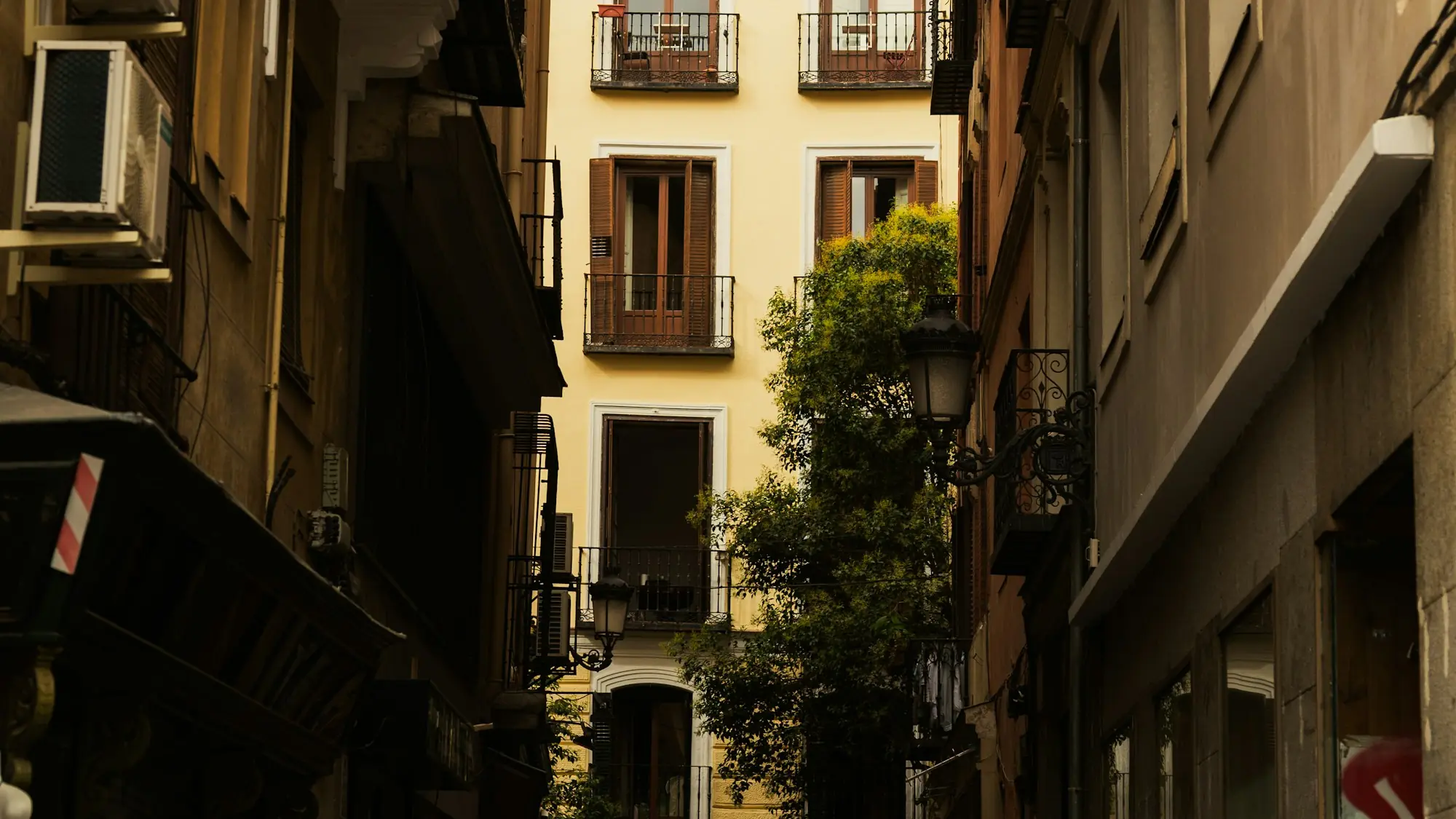 Calle estrecha de una ciudad española con balcones de forja y faroles