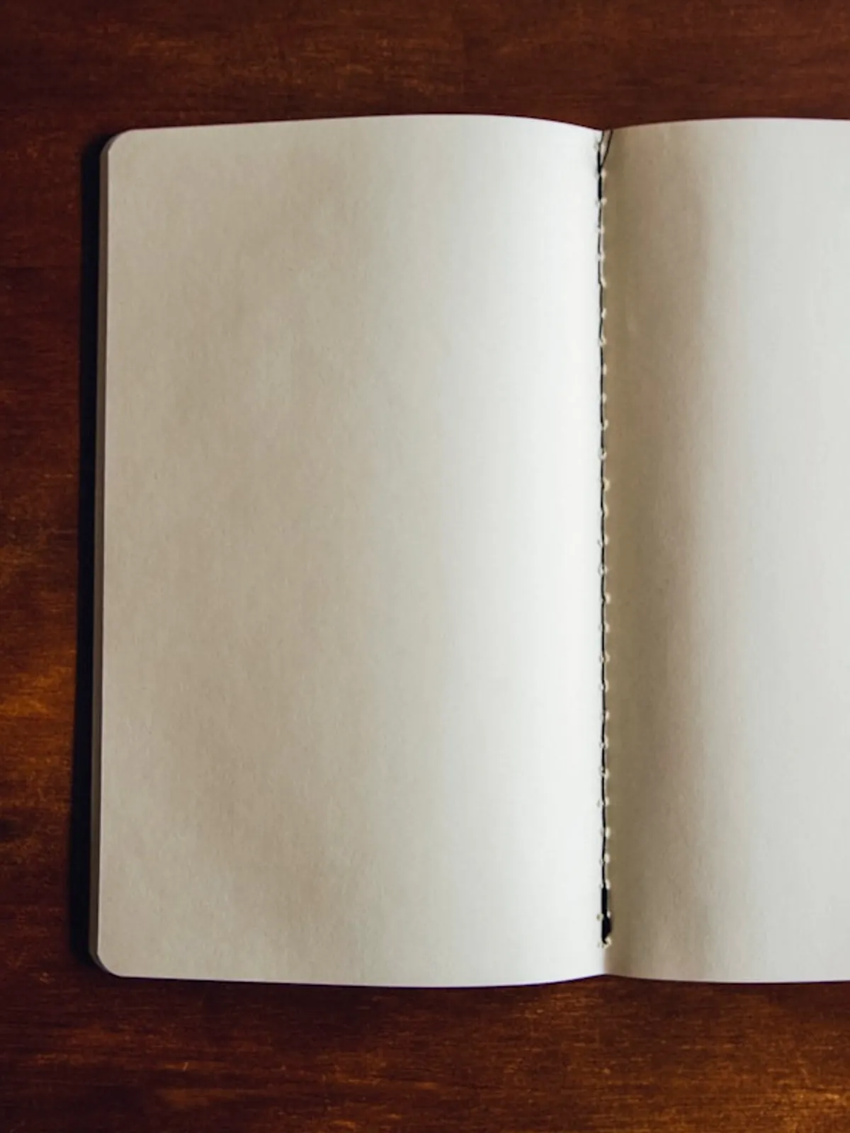 Cuaderno abierto con las páginas en blanco sobre una mesa de madera